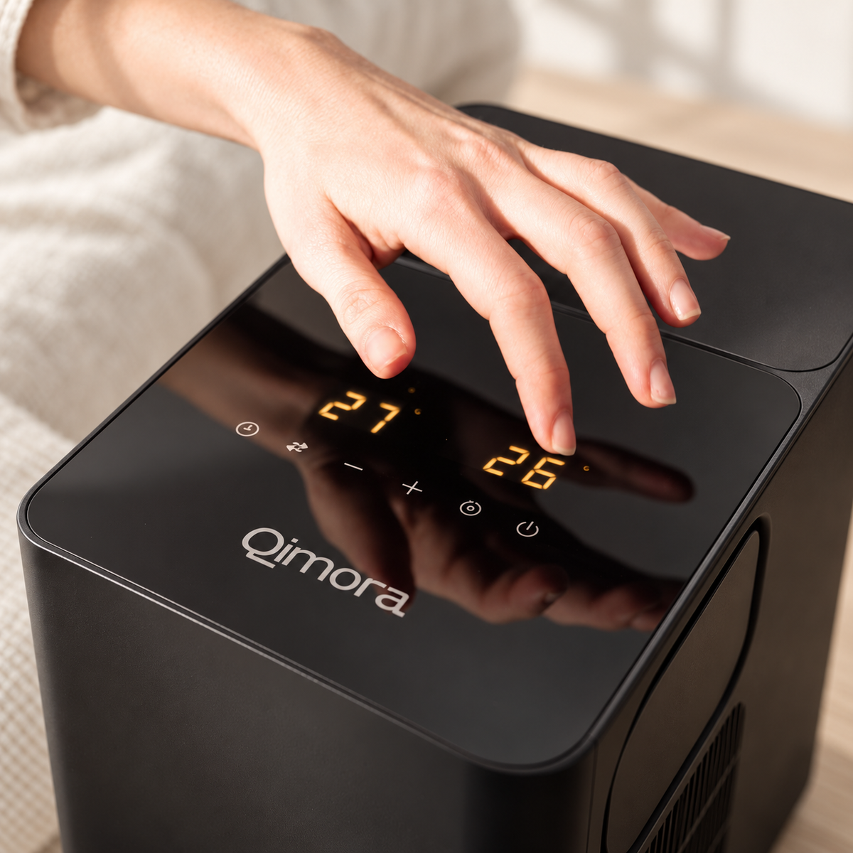 Hand on the Qimora Unit touch panel, one temperature display per side of the bed