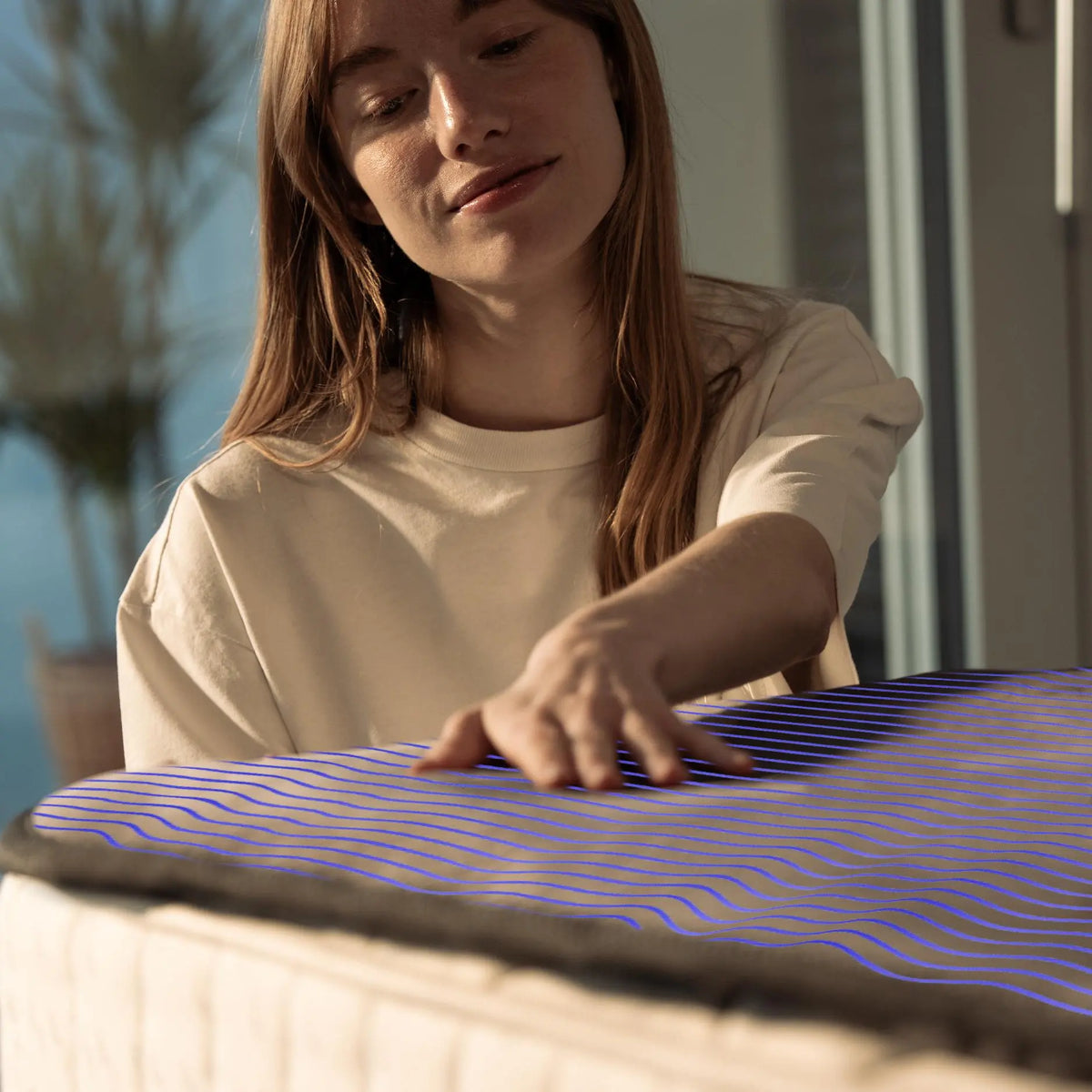 Woman touching the Qimora thermal Pad with its water channels highlighted on the mattress