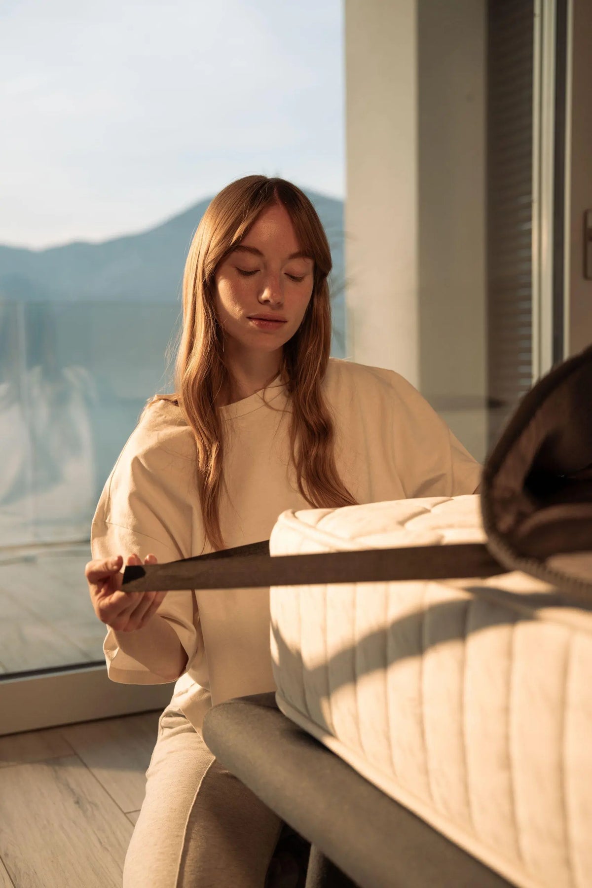 Woman securing the Qimora Pad to the mattress with its elastic straps