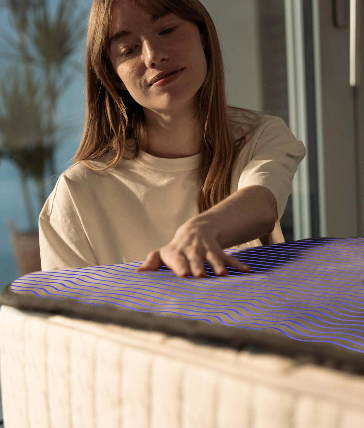 A hand resting on the Qimora Pad on a mattress